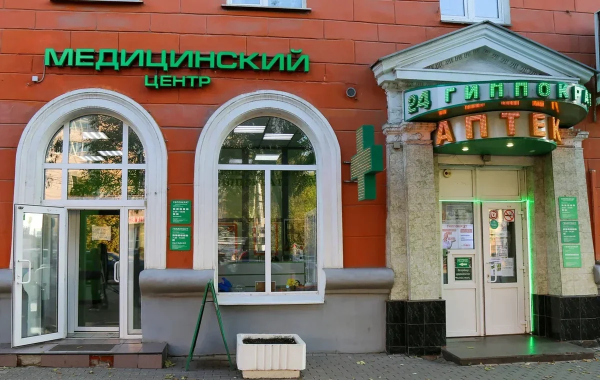 Вход в медицинский центр под зелёной вывеской «Медицинский центр» рядом с аптекой «Гиппократ»